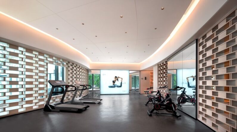 Een persoon die een loopband gebruikt in een moderne sportschool, op zoek naar de beste aanbiedingen online.
